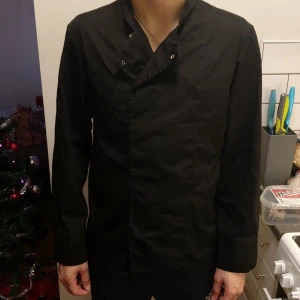 Svart kockskjorta  - Säljer mitt exs kockskjorta i storlek 48/L. Bra för dig som behöver en kockskjorta till matlagning. 