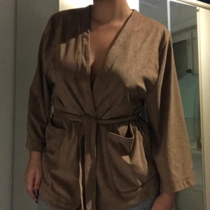 Kofta - Skön och lyxig kofta i lent mocka-material. Beige/brun färg. Använd fåtal gånger. Säljes pga att jag inte använder längre. Köparen står för frakt!