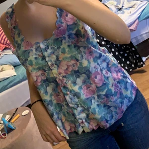 Blommigt linne - Ett superfint sommar linne i fint skick. Blommorna har starka färger. Det står att den är en S men jag skulle säga att den är en M då den är väldigt bred och har långa band☺️ OBS! Köparen står för frakt!!!💕