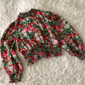 Blommig topp från Zara XS - Blommig topp från Zara. Köpte den i somras. Oanvänd men provad (jag har dock tagit bort de små puffarna i axlarna). Öppning i ryggen med ”polokrage”. Frakt tillkommer. 