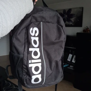 Adidas ryggsäck - Använd men i bra skick. Rymmer mycket. Längd: ca 40 cm. Bredd: ca 28 cm                                                                     Frakt tillkommer