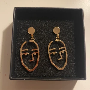 Örhängen  - Ett par fina guldiga örhängen, OBS kameran speglas i smycket