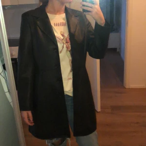 Läderkappa/skinnjacka  - Kappa i fejkläder som jag köpt secondhand på Humana i Barcelona. Inga defekter ser ut som ny! Står storlek L/42 men skulle säga att den passar S-L.