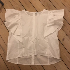  - Blus med volanger på ärmarna. Fina knappar bak. Storlek small