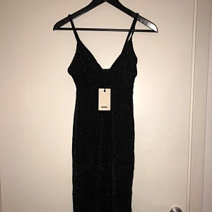  - Svart klänning med glittertrådar. Tight men stretchig, formar kroppen och framhäver formerna. Passar xs-s