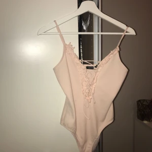  - Jätte fin rosa body med brodering och snörning. Väldigt liten i storleken så passa nog även dem som har 32 
