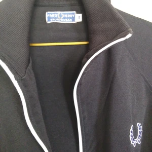  - Träningsjacka från Fred Perry i herrmodell, storlek S. För dam sitter den som en L. Tyvärr är blixtlåset av, men det går att laga för inte alltför mycket.  Säg till om du vill att jag tar den till lagning innan köp! Gratis frakt!