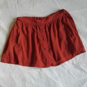 Kort kjol i rostrött/orange tunt tyg i lager. Safety shorts inbyggda! Små fickor. Betalning sker helst på Swish och frakt tillkommer.