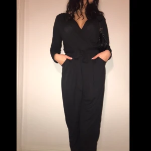 Svart byxdress från ginatricot - Snygg byxdress i nyckick! Storlek är L men passar likabra på mediummodell (se bild) då den är stretchig. 