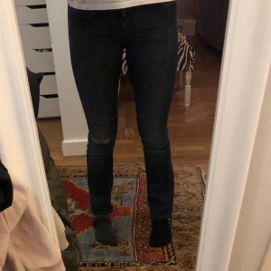 Mörkblå jeans - Mörkblåa jeans med ett hål på ena knäet och med en liten bootcut. 