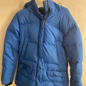 Everest Vinterjacka - Tjock blå vinterjacka med fyra fickor framtill, två innerfickor och en ficka för hörlurar. Den har samt en elastisk mudd med tumhål i ärmsluten. Perfekt till en kall vinterdag. Storlek 38 och priset för 300kr💖