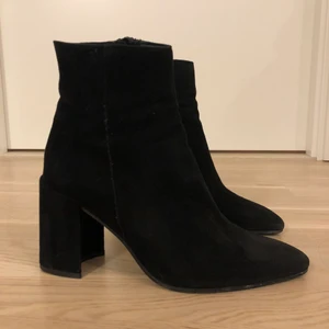 K.COBLER Yeo stövletter svarta (nypris 1600kr)  - Yeo, en feminin stövlett från K.Cobler i exklusiv svart mocka. Den månformade klädda klacken är ca 9 cm hög och stövletten knäpps på insidan med dragkedja. Inuti är skon fodrad med skinn, även innersulan är av skinn. Yttersulan av gummi. Stövletten är tillverkad i Italien av material i högsta kvalitet. K.Cobler är modemärket med spännande globala influenser och unik design. Sparsamt använda. Läs mer: https://www.scorett.se/dam/skor/stovletter/yeo-2?nosto=productcategory-nosto-2#product-custom-tabs