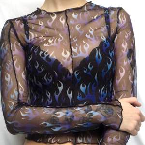 En svart transparant mech-tröja med ett mönster av blå och lila eldflammor💙stretchigt material💜använd ett fåtal gånger så i väldigt bra skick💙 lite halvt volangiga kanter💜 frakt ingår ej utan kostar 42kr💙 säg till om det finns några frågor💜