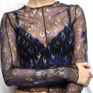 ✨Blue flame top✨ - En svart transparant mech-tröja med ett mönster av blå och lila eldflammor💙stretchigt material💜använd ett fåtal gånger så i väldigt bra skick💙 lite halvt volangiga kanter💜 frakt ingår ej utan kostar 42kr💙 säg till om det finns några frågor💜