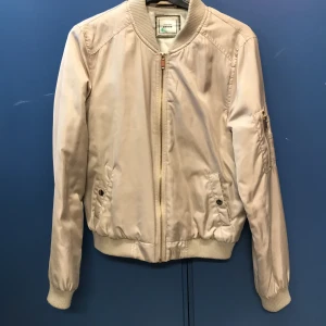 Bomberjacka  - Beige sommar/vår bomberjacka, den är oanvänd och i bra skick. Skulle säga att den passar dem som har storlek XS-S. Säljer denna för 350kr-500kr. Köparen står för frakten. Kan tänka mig att gå ner i pris vid snabb affär  
