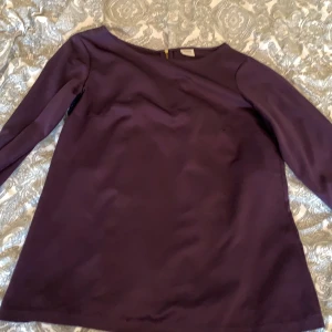 Mörklila blus  - En mörklila blus med en dragkedja. 