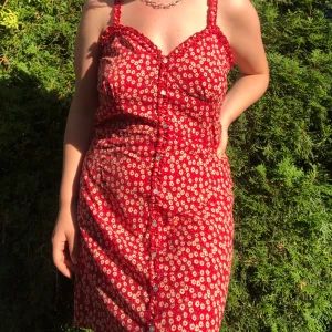 Röd klänning med vita blommor - köpte klänningen i barcelona och har bara använt den en gång, mycket bra skick. storlek L och är inte elastisk i materialet 💘 klänningen har en (icke synlig) dragkedja på sidan ovanför midjan som bättrar passformen, men den sitter löst på mig (storlek M)