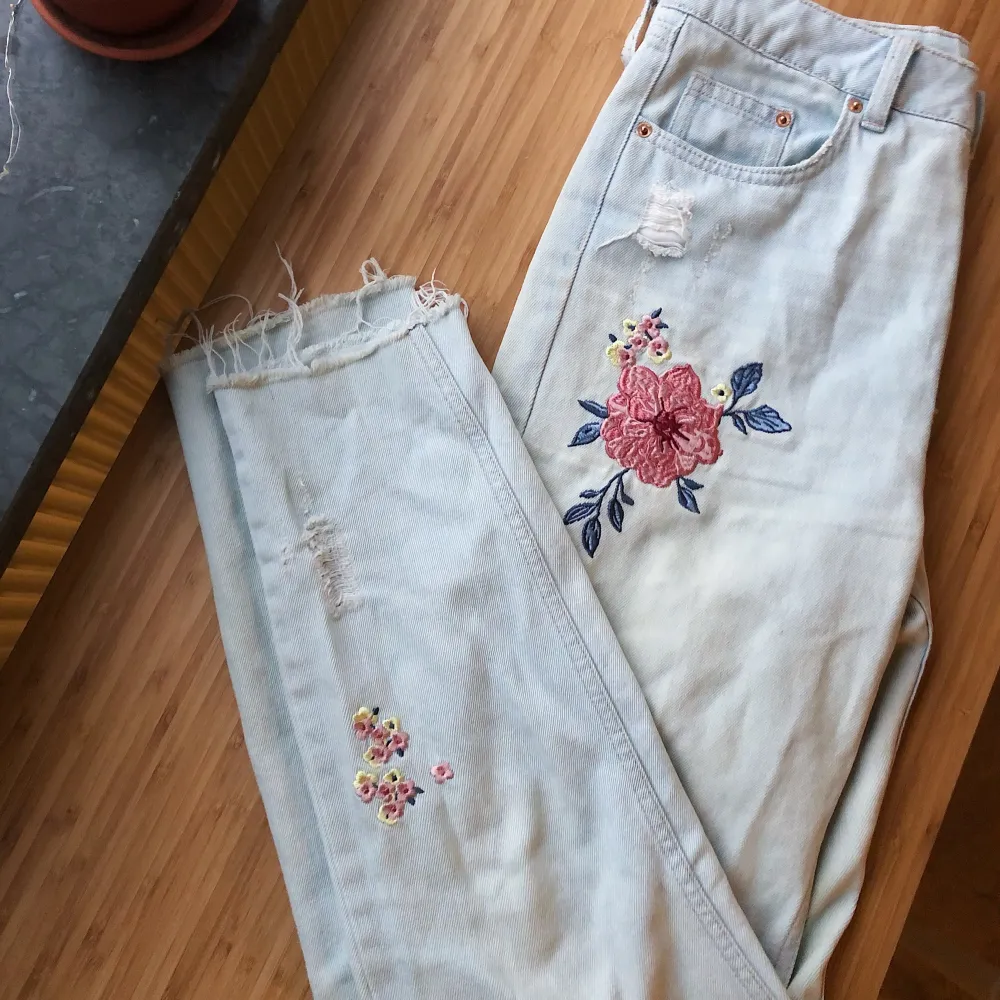 Ljusa jeans med rosa blommor på två ställen och slitningar nertill samt på en bakficka. Raka i benen och hög midja. Jag är 172 lång. Frakt tillkommer! . Jeans & Byxor.