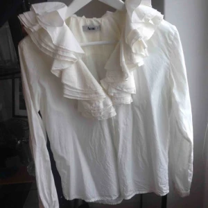  - Underbar vit (inte kritvit, mer crémevit) blus från Acne. Storlek 38.   Säljer den för att jag aldrig använder den. Dolda knappar, knapp längst ut på ärmen, härlig volym i kragen. 100% bomull.  Tål 30 grader maskintvätt. Ord.pris 1500kr.