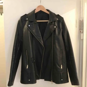  - Längre skinnjacka (fakeskinn) perfekt till nästa månads väder! Snygg på eftersom den är rak och lite längre. Fint skick! 