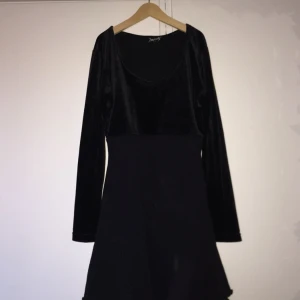  - Långärmad klänning med skärning under bysten. Överdel i glansig plysch och underdel i stretchigt material. Strl XS. 