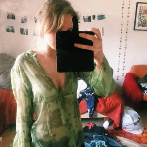  - Tunn blus med djup urringning i grönt med mörkare gröna mönster. Det var svårt att få fram färgen på bilderna, men bild 2 gör den mest rättvisa. Köparen betalar frakt. 