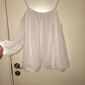  - Vit offshoulder blus i volanger från Nelly. Långärmad.