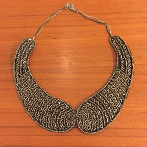  - Ett silvrigt halsband som ser ut som en krage.