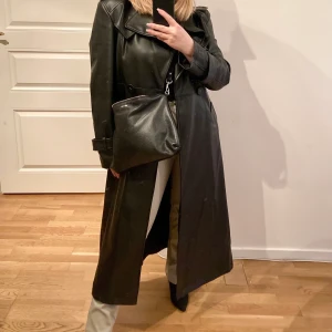 Lång skinn kappa storlek 36 - Lång skinn kappa  från Gina Tricot. Storlek 36 men passar en 34 och 38 också beroende på hur man vill att den ska sitta. Oanvänd.