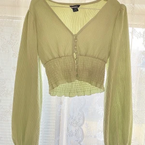 Grön blus  - En croppad blus som tyvärr inte kommer till användning! Varan är i inprincip nyskick och har använts två gånger. Blusen har inte några defekter. BUDGIVNING I KOMMENTERARERNA!!! Buda minst 10 kr. AVSLUTAS IKVÄLL 7/2 kl 23:59 🧚🏼🧚🏼 Högsta budet just nu: 150 kr