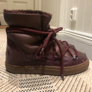 Inuikkii låga vinröda - Låga inuikkiis i färg vinröd/metallic. Använda förra vintern, men i bra skick. Nypris ca 2600kr.