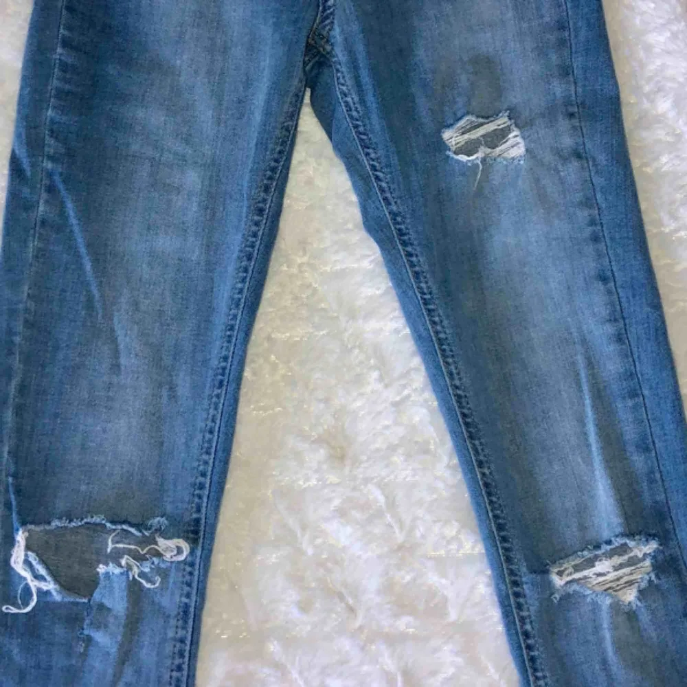 Ett par tighta, ljusa jeans, köpta från Gina Tricot. Passform Molly. Två bakfickor, inga fickor fram. Två hål på knäna och ett litet hål mitt på låret (ska vara där). Ändarna längst ner är ripped. Betalas med Swish och köparen står för frakten☺️. Jeans & Byxor.