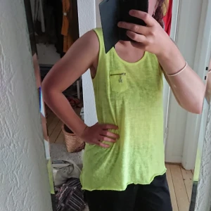  - Neon färgat linne i gott skick, coolt mönster baktill, kedja bak, passar medium stlk. Frakt tilläggs. 