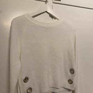  - Vit, något croppad tröja med metaldetaljer. 