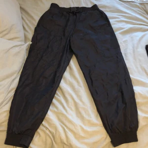 Zara byxor strl M - Byxor från zara i strl M. Regn/vind material. Nyskick, använda  1gång. Super coola byxor som jag lätt skulle vilja ha kvar men anser att jag har för många byxor. Spänne fram vilket är en snygg detalj. Fake fickor bak och riktiga fickor på sidan av byxorna