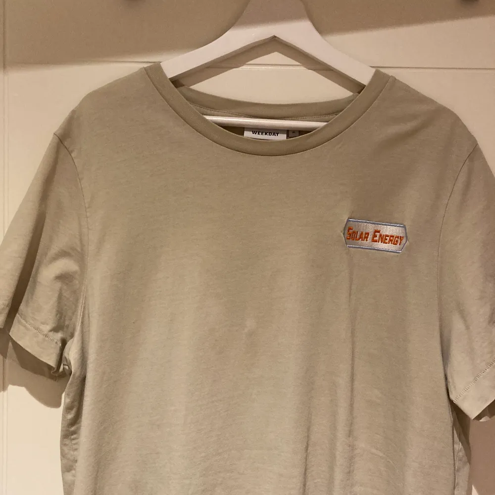 Beige oversized t-shirt från Weekday. Trycket ”solar energy” på framsidan och ”24/7 hours” på baksidan. Använd ett par gånger men fortfarande i bra skick!. T-shirts.