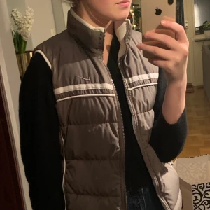 Nike vintage väst - Vintage väst från Nike. Svin najs. Den är olivegrön/beige/grå men man kan vända den ifall man tröttnar på färgen, då blir den klassiskt vit. Väldigt fräsch och läcker men samtidigt lite tuff. Storlek L men passar M också
