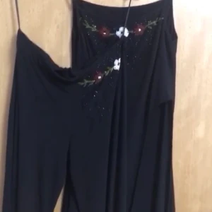 En svart set  - En svart byxa med en en svart top i samma modell. Settet har rosor som detaljer i pärlor. Den har storleken 42 och är använd 1 gång. Det kostar 500kr styck 