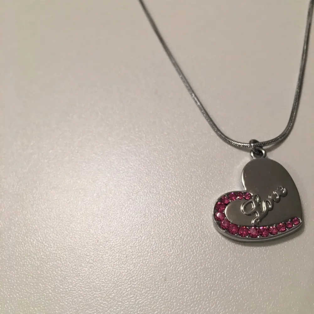 Silvrigt halsband med ett hjärta som detalj, och rosa små diamantstenar. Aldrig använd. Köparen står för frakten 🍂. Accessoarer.