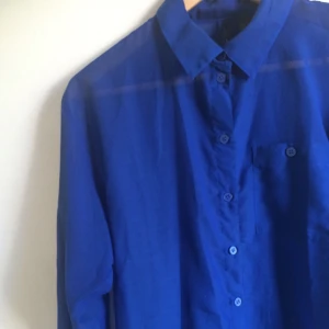  - Kornblå transparent skjorta köpt på h&m i storlek 34. Stor i storleken dock så för mig som vanligtvis är 34-36 är den loose. Bröstficka på vänster sida. 
Gjord i polyester.  