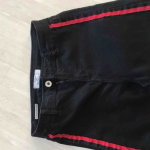  - Svarta jeans med röda sträck på sidorna. Jag är storlek 25 så dom är stretchiga och passar fler storlekar. Inte mycket använda. Bara att skriva för fler frågor men frakt tillkommer