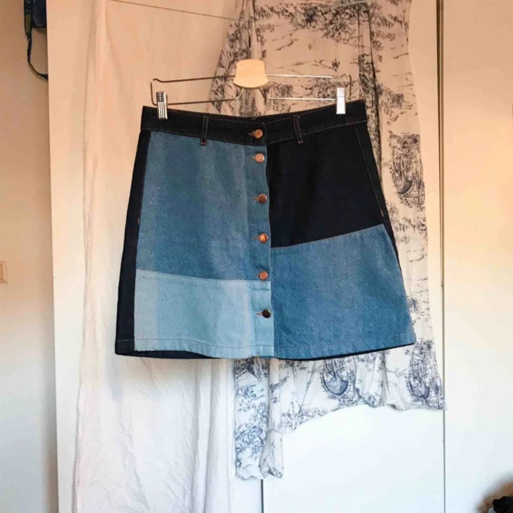 En kort jeanskjol med patchwork i olika nyanser av denim samt knäppning fram. Kjolen är i använt men gott skick. Köparen står för frakt ⚡️. Kjolar.