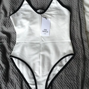 Body - Vit body med svarta kanter. Oanvänd, lappen kvar. Fin till jeans eller kjolen. Köparen står för frakt. 