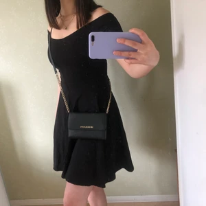 Svart basic klänning  - En svart basic offshoulder klänning i trikå från ginatricot. Den är lite av en skaterklänning och är ganska lös från midjan och ner vilket får midjan att framstå som smalare. 
