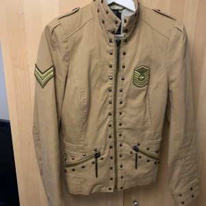 Jacka i rockig stil - En skön jacka med tuff stil. Osäker på hur gammal den är. Men sparsamt använd iallafall. Storlek är E42, men passar nog även lite mindre också. Finns i Uppsala. Frakt tillkommer om du vill att jag ska skicka.