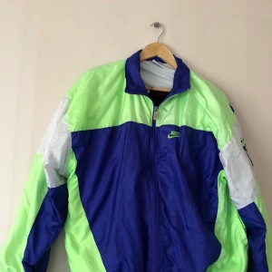 Nike windbreaker L - Nike windbreaker super vintage from the 1980s (NIKE INTERNATIONAL) in colors green,blue and white in size L. In perfect condition no rips at all. 