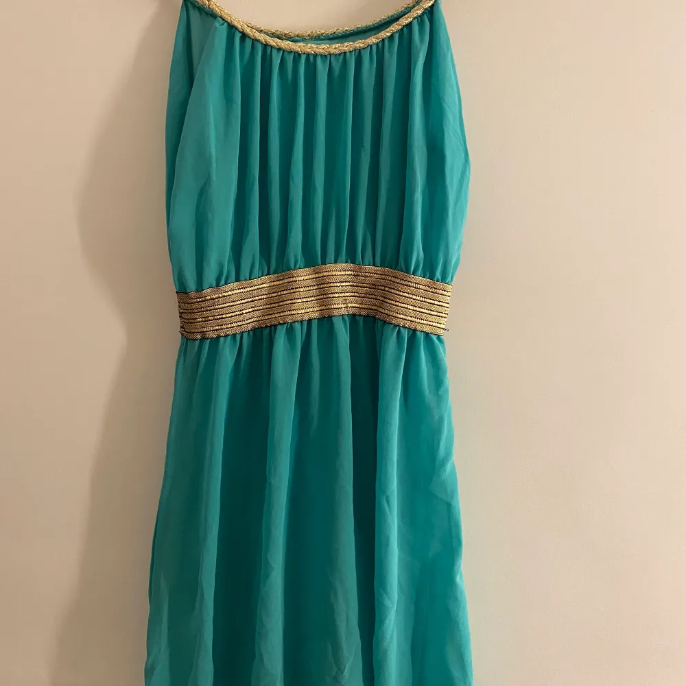 Turkosblå klänning med guld detaljer som är längre i bak, köparen står för ev frakt . Klänningar.
