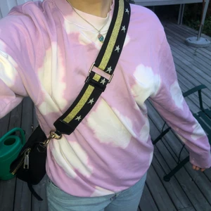 Marc Jacobs Väskband  - Ett Väskband från Marc Jacobs i guld och svart med silver stjärnor. Justerbar längd. Kan sättas på alla väskor med inte endast Marc Jacobs. Därför kan du byta ut original bandet till detta supersnygga! Bra skick men lite av guldet är avskrapat längst ner på klämman därför endast 500 kr. Säljer då det inte kommer till användning:( Väldigt skönt att ha på sig även till tunga väskor då remmen är så pass bred. Köpt på NK i Stockholm för 1090 kronor!! Fråga gärna för mer bilder! 🥰