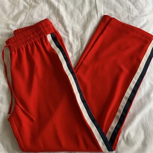 Röda kostymbyxor med revär - Långa fina kostymbyxor med blå och vit river på sidorna 