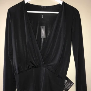 Oanvänd body från Nelly storlek S - Svart långärmad oanvänd body med lapparna kvar.